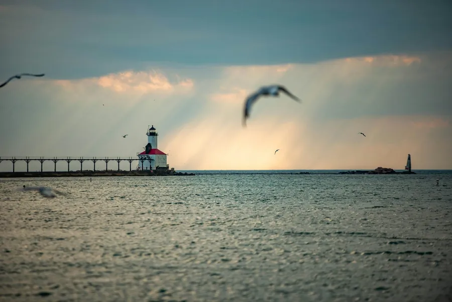 A Lake Michigan pier light with gulls over the water